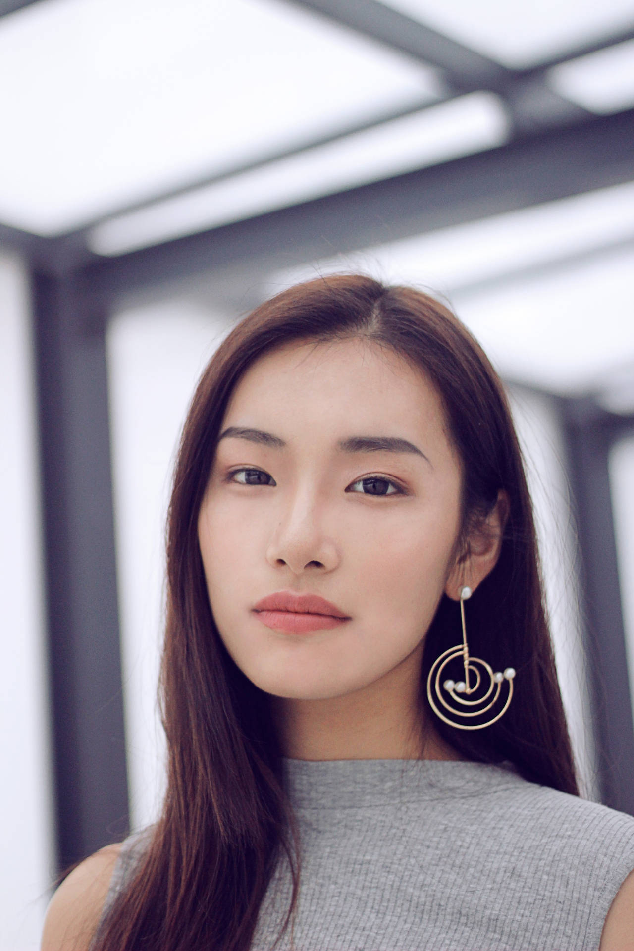 年輕女性戴螺旋耳環在現代玻璃結構中