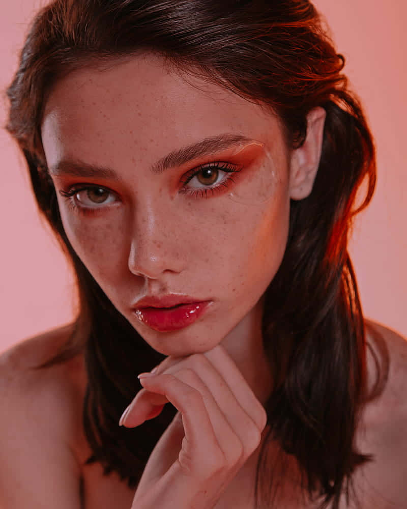 有雀斑和紅色妝容的女性直視鏡頭。