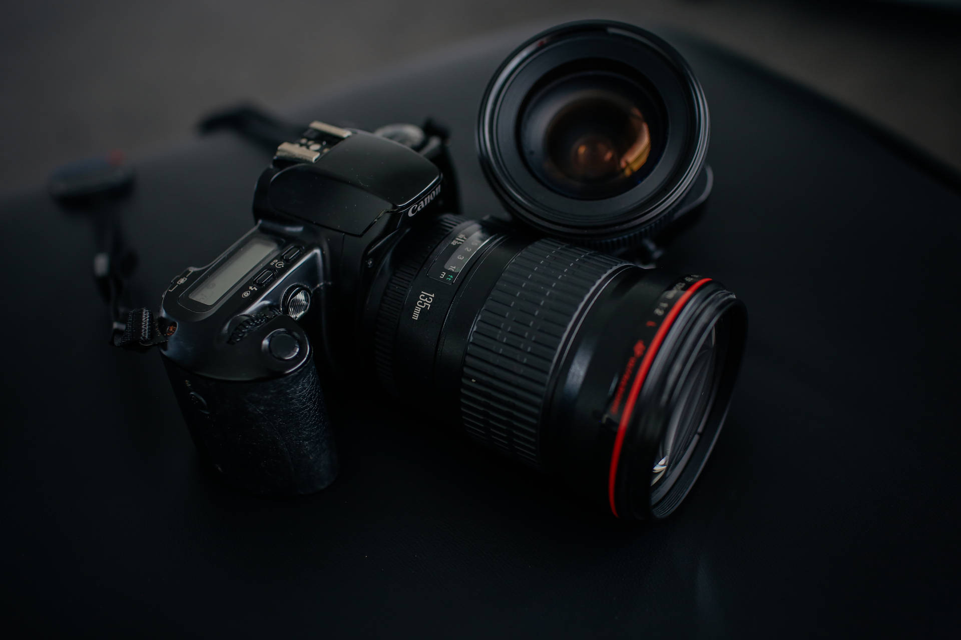 專業 DSLR 相機和鏡頭在工作室燈光下的深色表面上