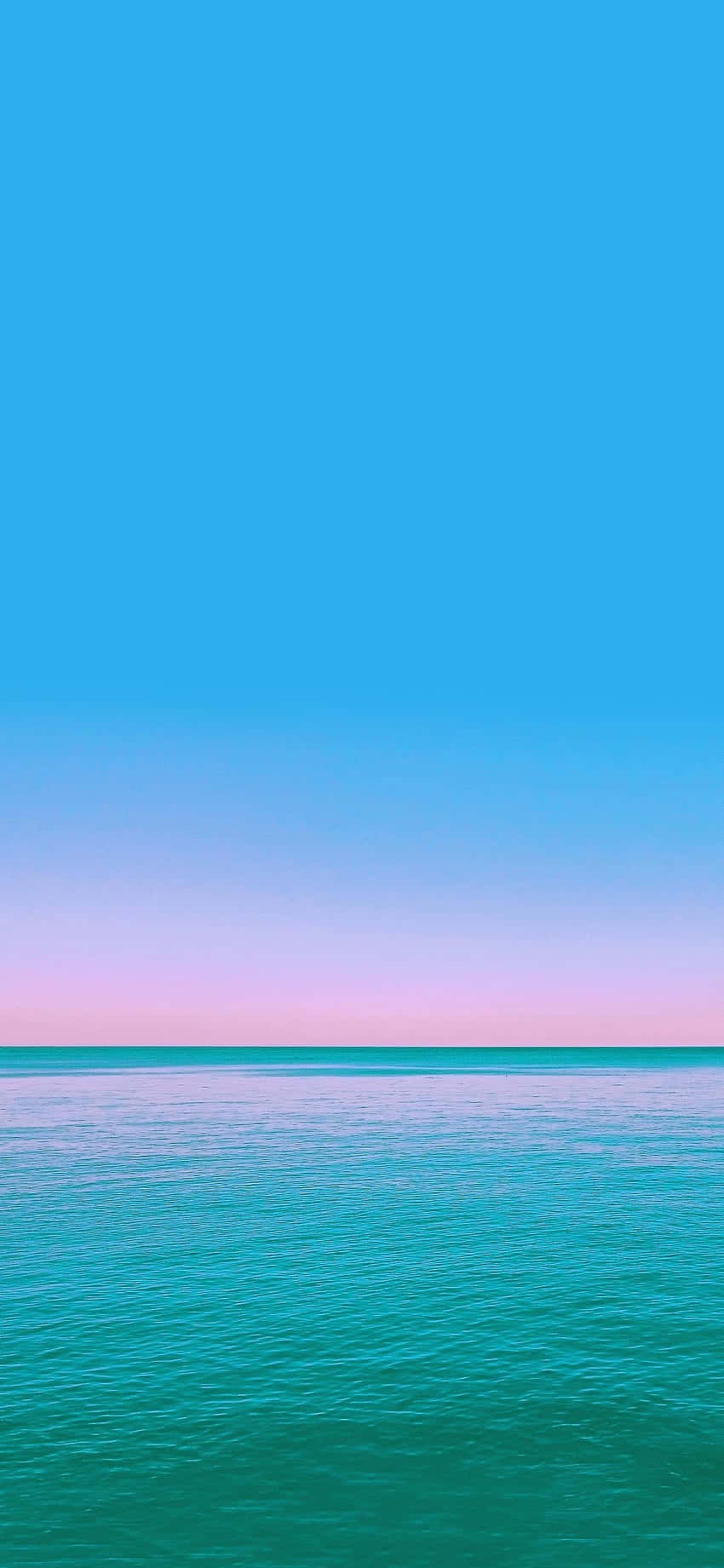 平靜的海洋在暮色地平線上與粉彩天空相遇