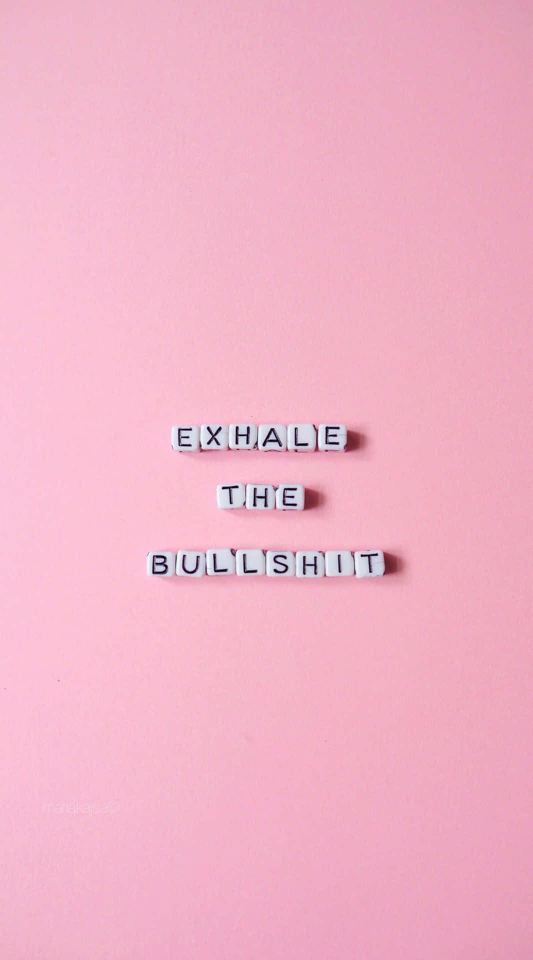 白色字母瓷磚在粉紅色背景上拼出 exhale the bullshit。