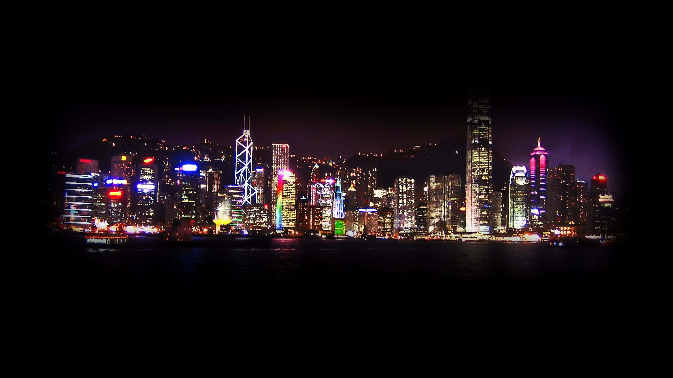 使用這款絕美美學 YouTube 頭版展示你的內容 壁紙 — 香港天際線的迷人夜景，霓虹燈閃爍的摩天大樓倒映在黑暗的水面上。