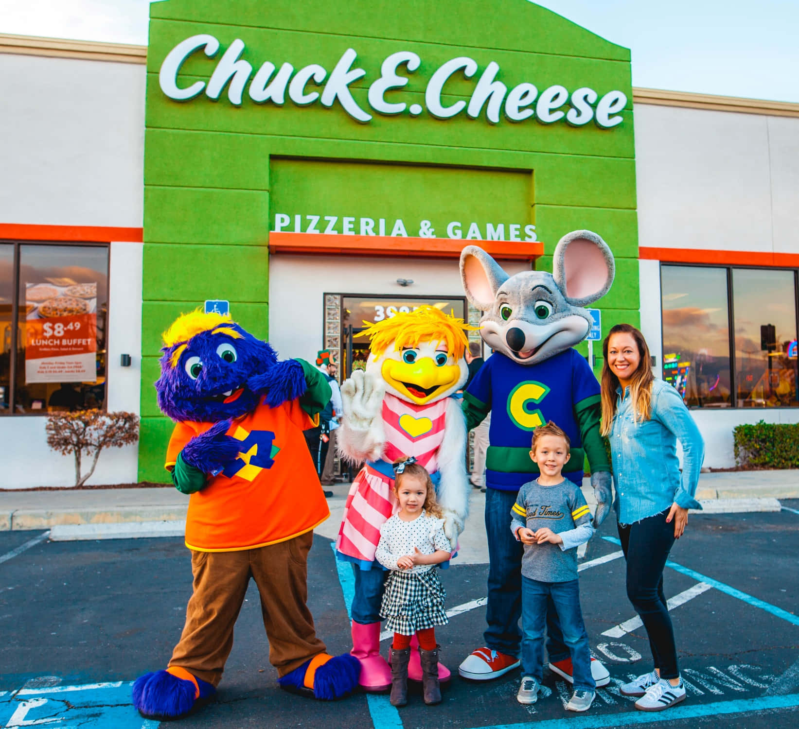 家庭與Chuck E. Cheese吉祥物在餐廳外日落時分。