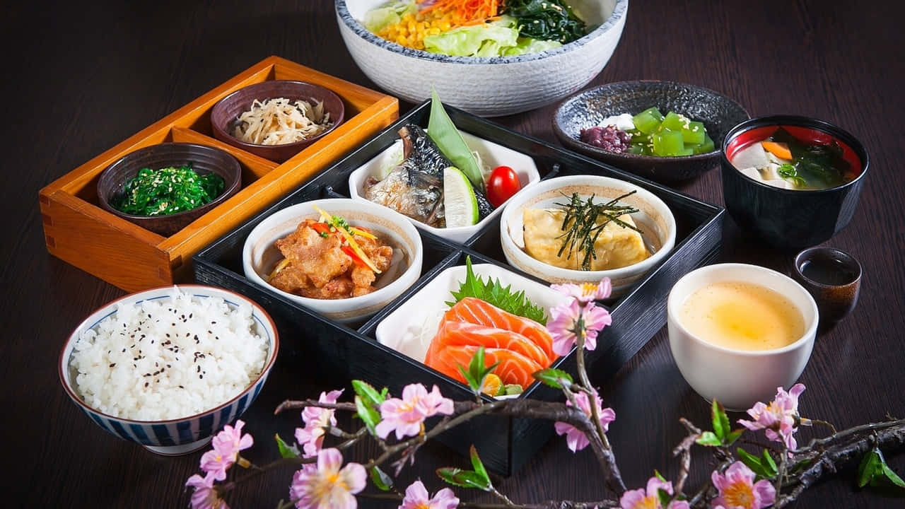 日本料理，配有便當盒、壽司、米飯和茶，周圍環繞著櫻花。