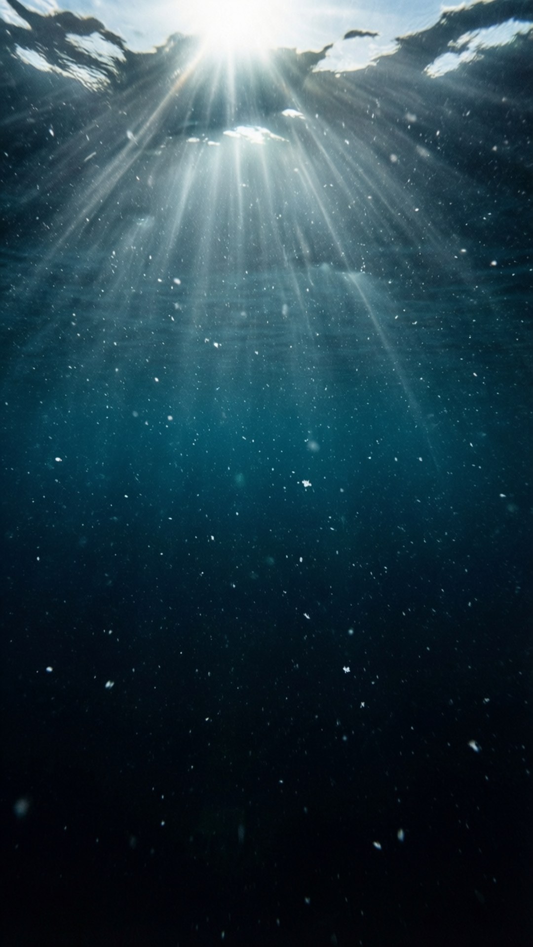 陽光穿過海面，照亮深藍色海水中的浮游粒子。