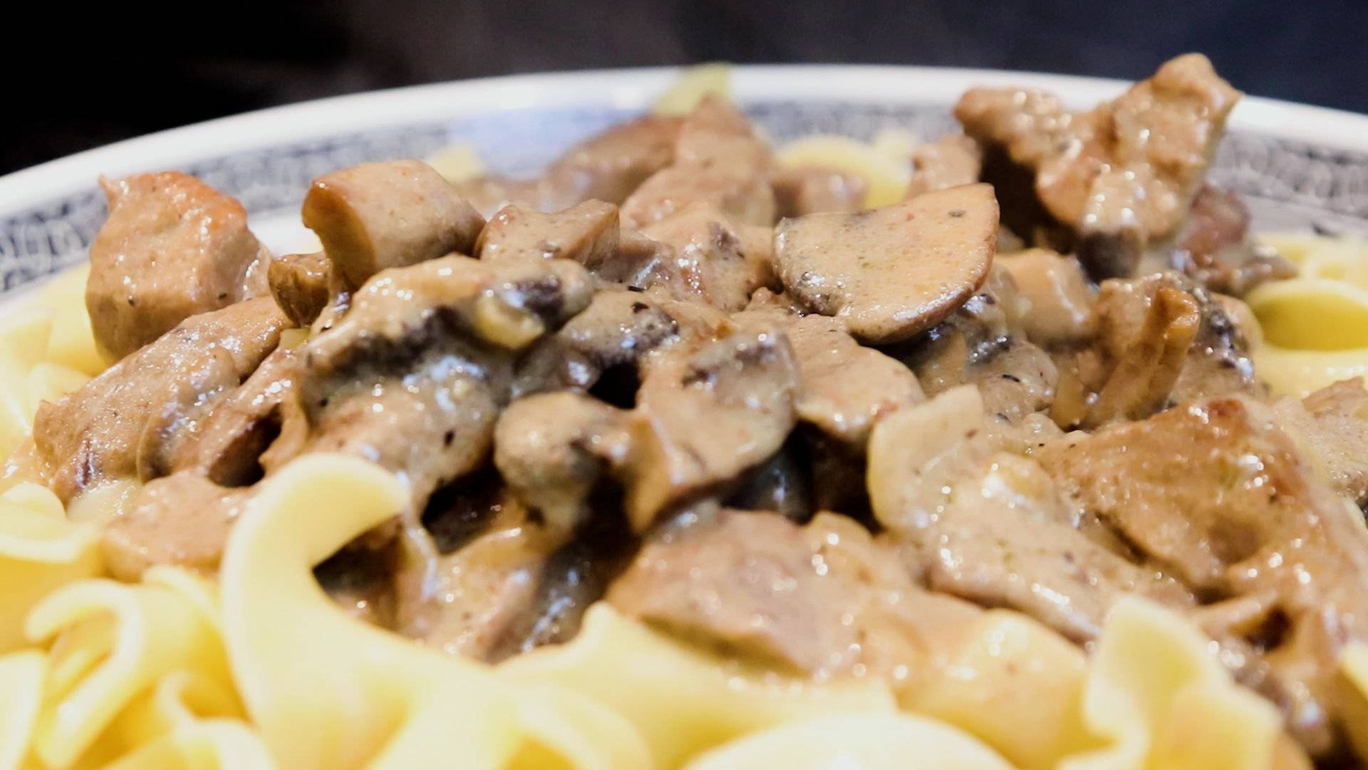 俄式牛肉斯特羅甘諾夫 壁紙 — 特寫鏡頭：奶油蘑菇牛肉斯特羅加諾夫配闊蛋麵，盛於有圖案的碗中。