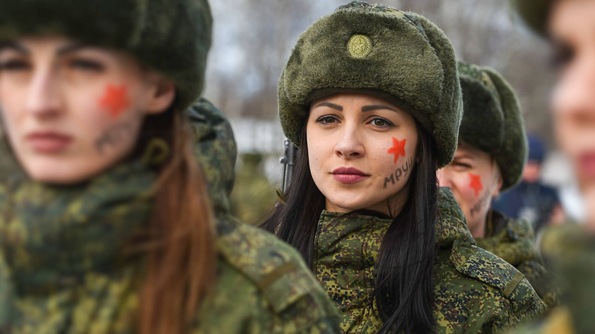 身穿軍裝、臉上畫著紅星的女性在冬季戶外站立。