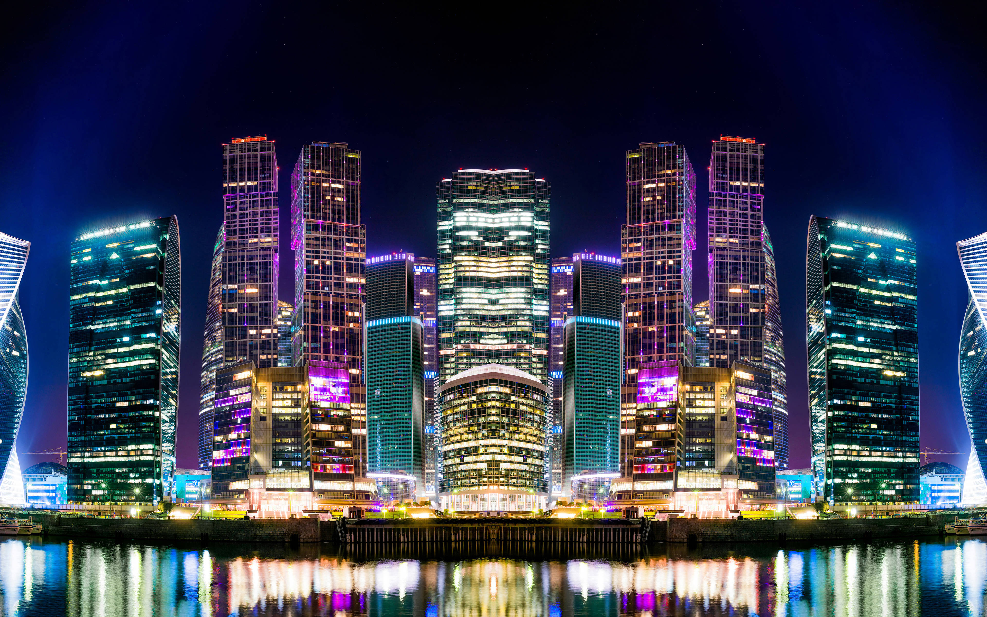 俄羅斯夜景城市風光 壁紙 — 高聳的摩天大樓閃爍著鮮豔的霓虹燈光，在深邃的夜空下平靜的水面上倒映。