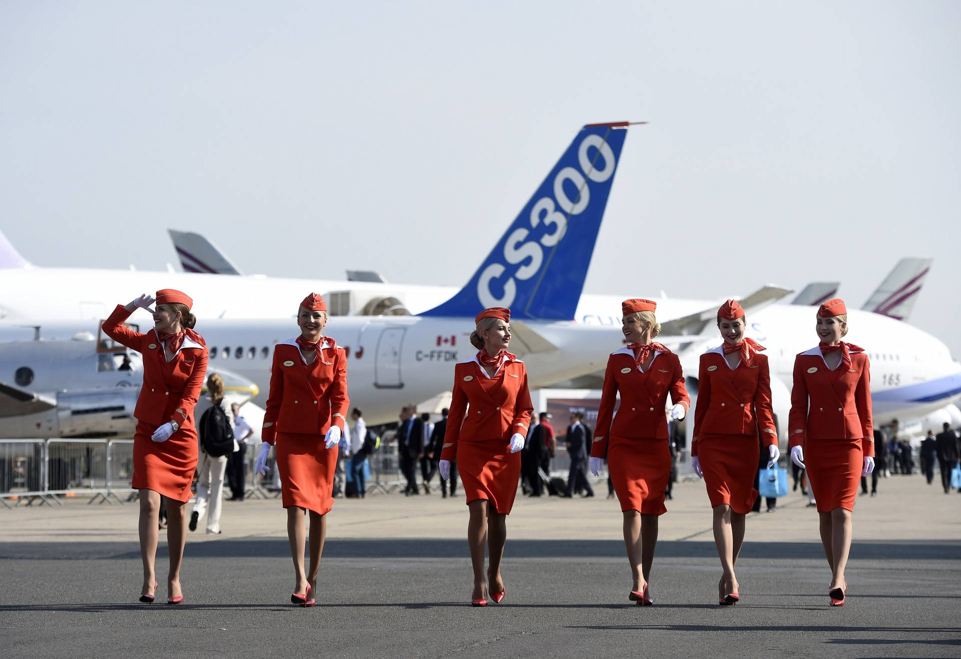 身穿紅色制服的空服員在機場停機坪上靠近飛機行走。