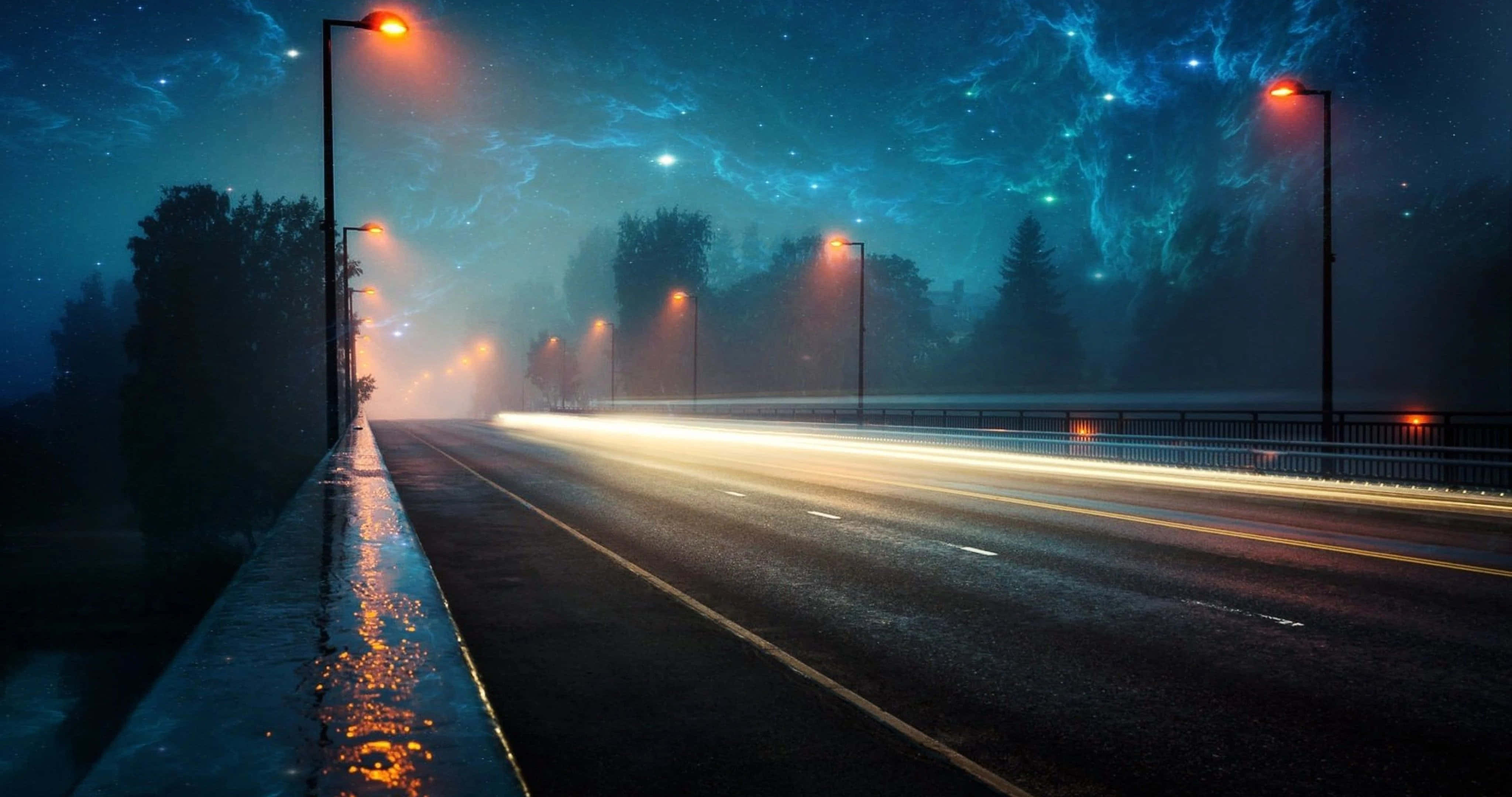 保持創意與生產力的美學桌面壁紙 壁紙 — 霧氣瀰漫的夜晚道路，在發光路燈下，有汽車燈光軌跡和星光閃爍的電藍色天空。