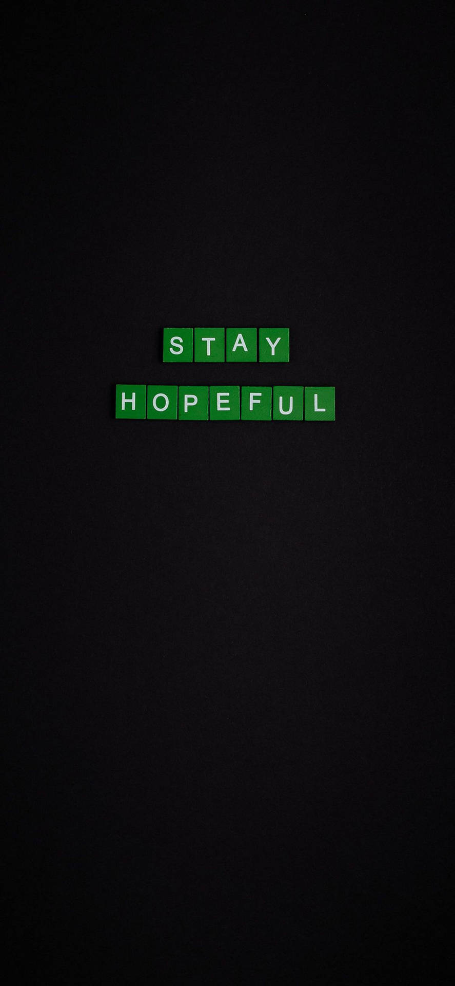 深色背景上帶有 stay hopeful 訊息的綠色拼字磚塊。