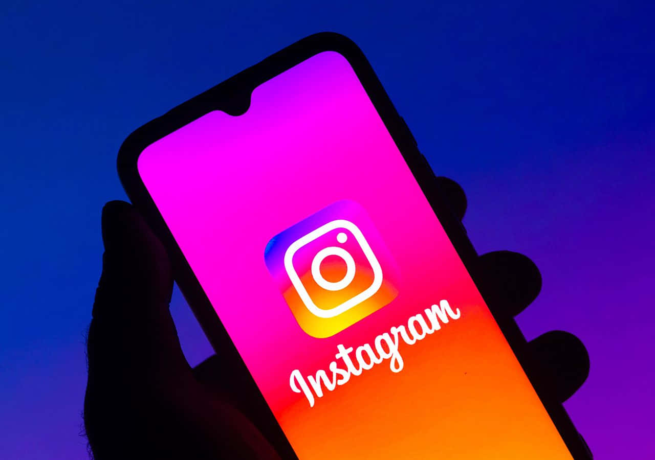 手拿著手機，Instagram應用程式標誌在屏幕上發光。