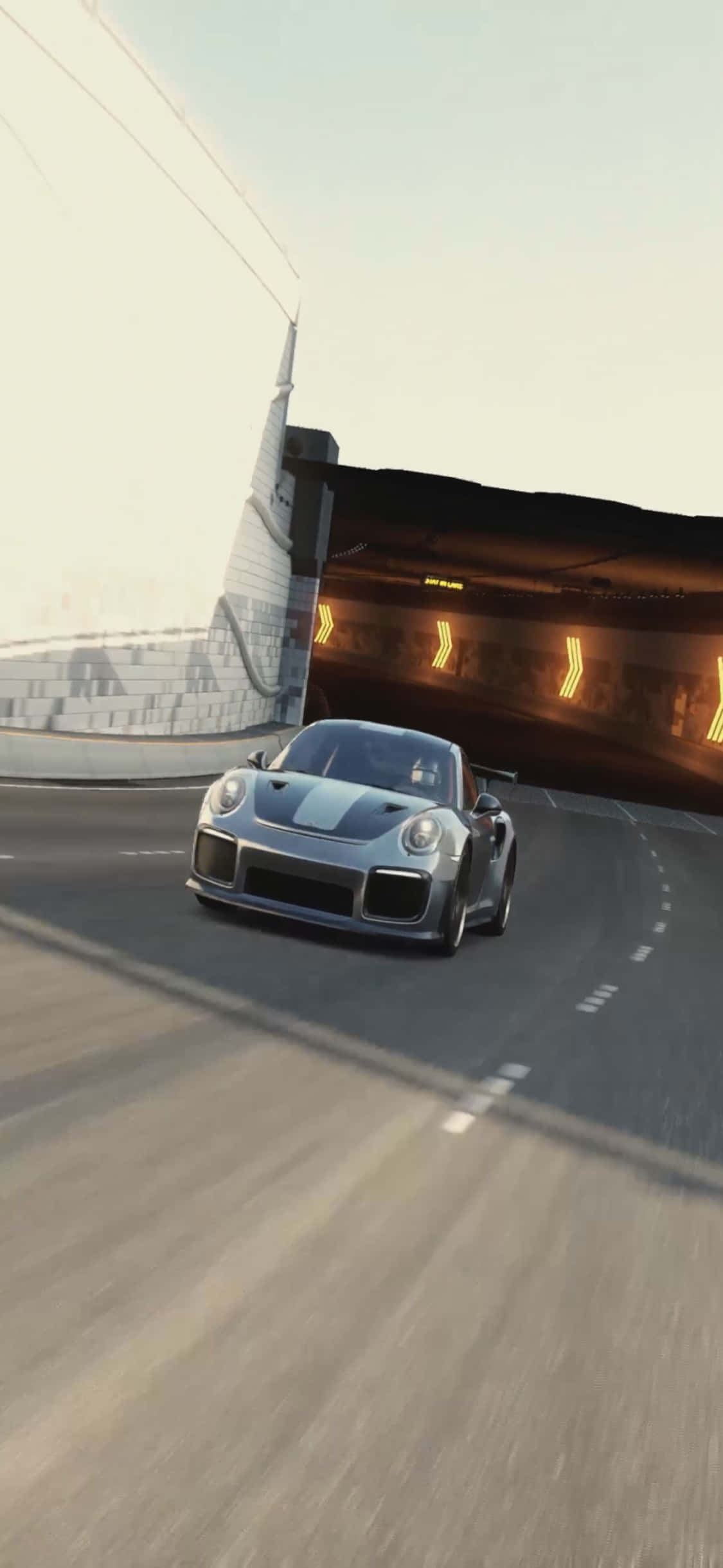 保時捷911 GT2 iPhone X《極限競速7》背景 壁紙 — 一輛銀色跑車在陽光明媚的高速公路上，以動態模糊效果疾速穿過隧道入口。