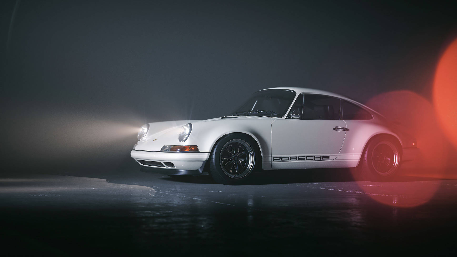白色保時捷911跑車，由工作室燈光照亮，帶有紅色鏡頭光暈。