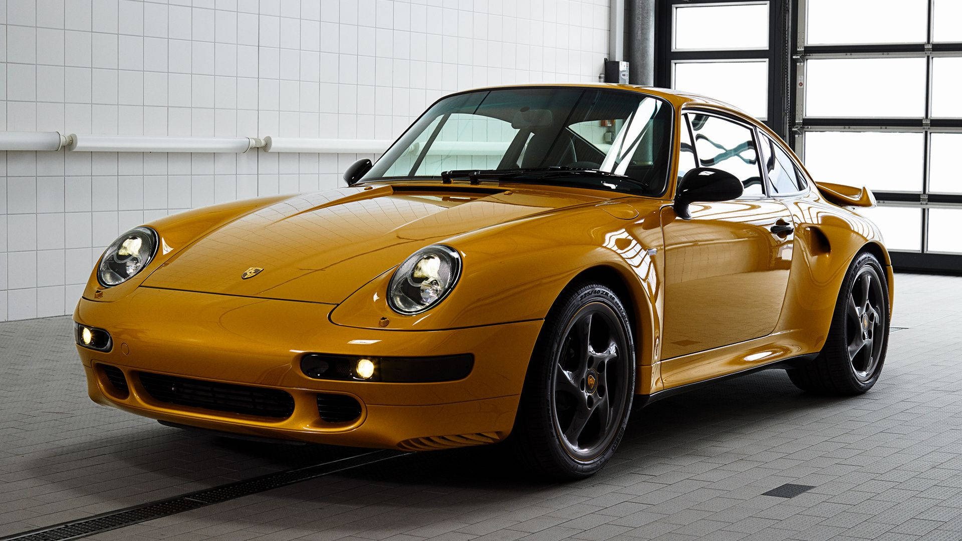 金色保時捷911 Turbo在乾淨的瓷磚車庫中，配有大窗戶。