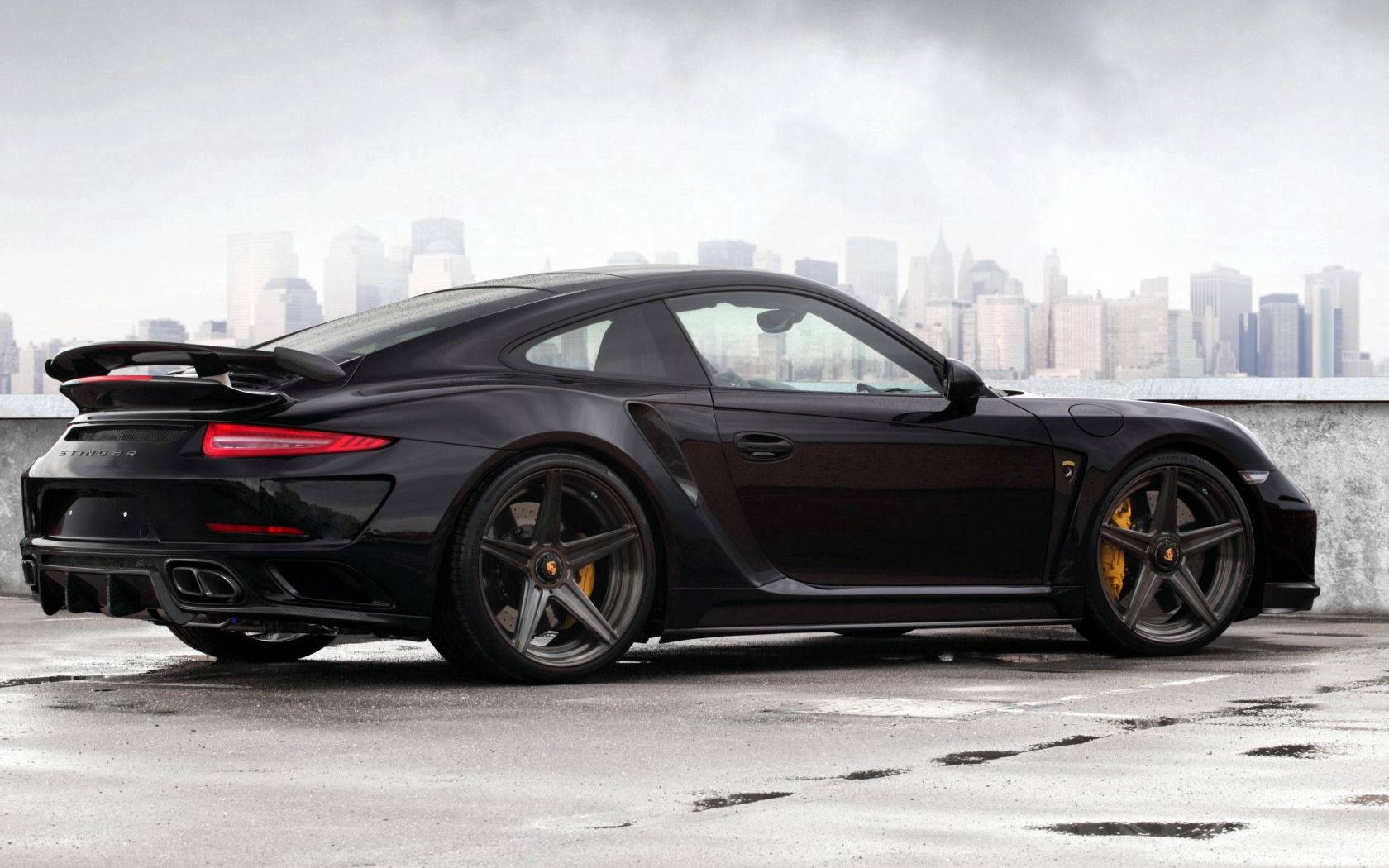 黑色保時捷911 Turbo S在屋頂上，背景是城市天際線。