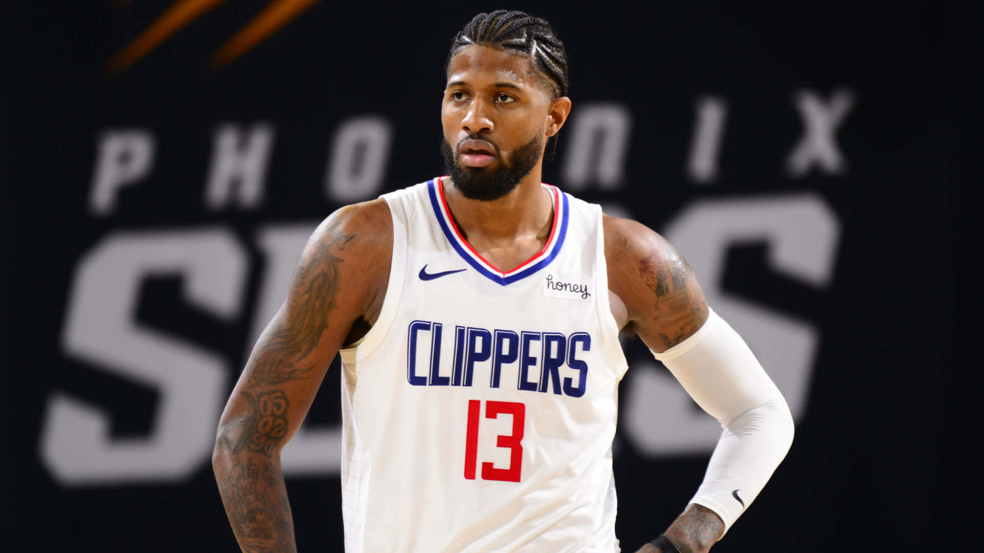 籃球運動員保羅·喬治身穿快艇隊13號球衣，帶有紋身和專注的表情。