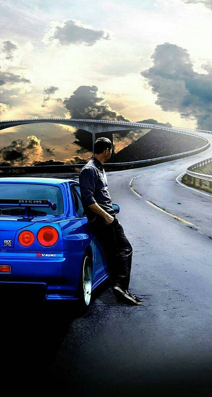 男人靠在藍色跑車上，蜿蜒山路，日落時分。