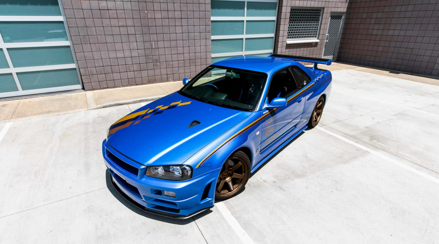帶有金色條紋的藍色日產Skyline GT-R停在混凝土停車場。