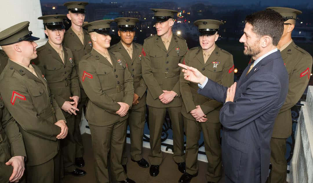 穿西裝的男子晚上在屋頂上與穿制服的海軍陸戰隊員交談。