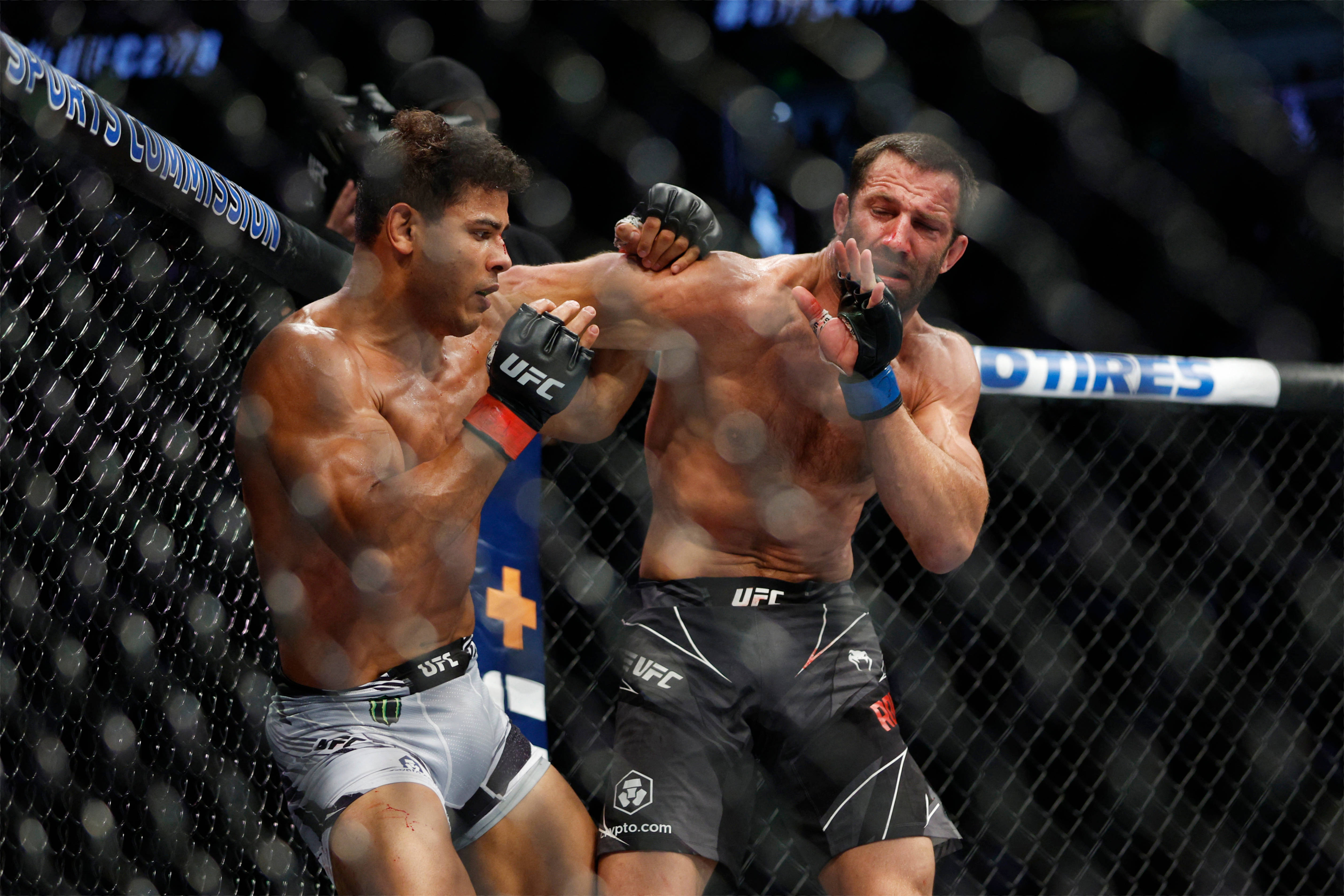 保羅·科斯塔格擋重拳 壁紙 — 兩名肌肉發達的MMA拳手在籠中激烈交鋒，汗水飛濺，其中一人使出強力肘擊。