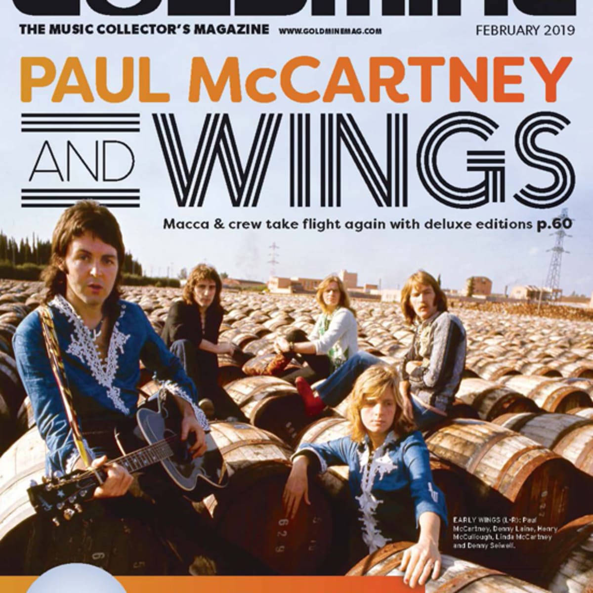 保羅·麥卡特尼與 Wings《Goldmine》雜誌2019年2月封面 壁紙 — Paul McCartney 與 Wings 在明亮的日光下，隨意地擺姿勢坐在一排排木製酒桶上。