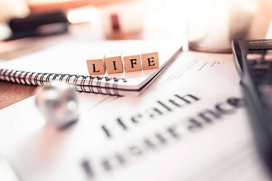 拼出LIFE的木塊放在健康保險文件上，旁邊有計算機。
