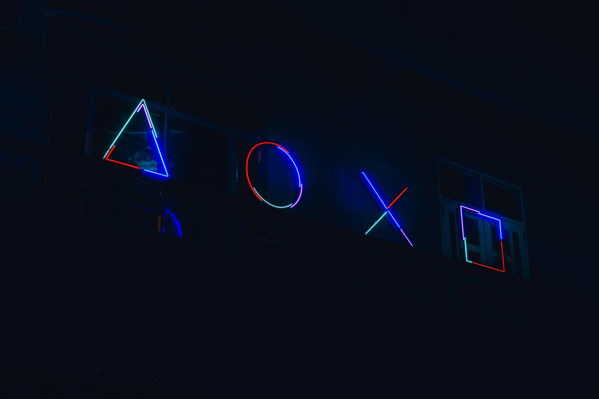 建築物外牆上夜間發光的霓虹燈PlayStation控制器符號。