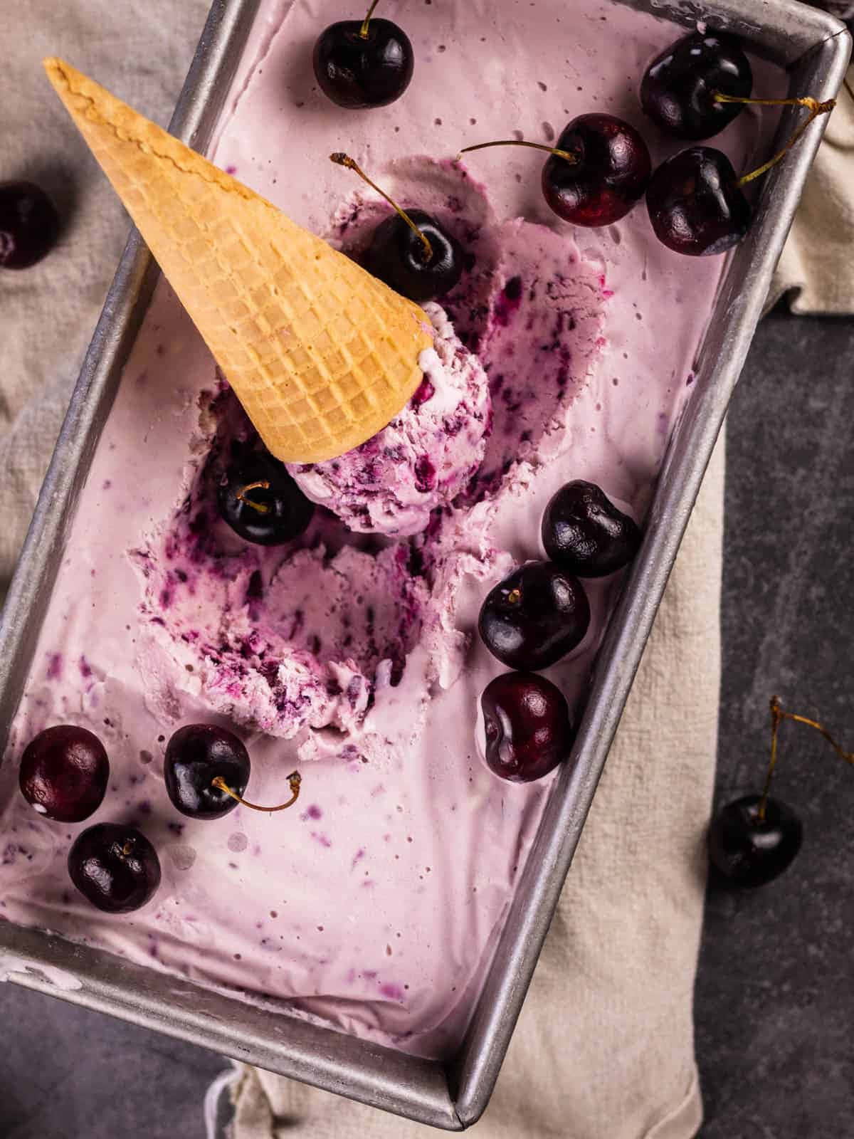 Black Cherry 桌布 壁紙 — 俯拍鏡頭：金屬麵包盤中的紫色櫻桃雪糕，上面鋪滿新鮮櫻桃和一個窩夫筒雪糕球。