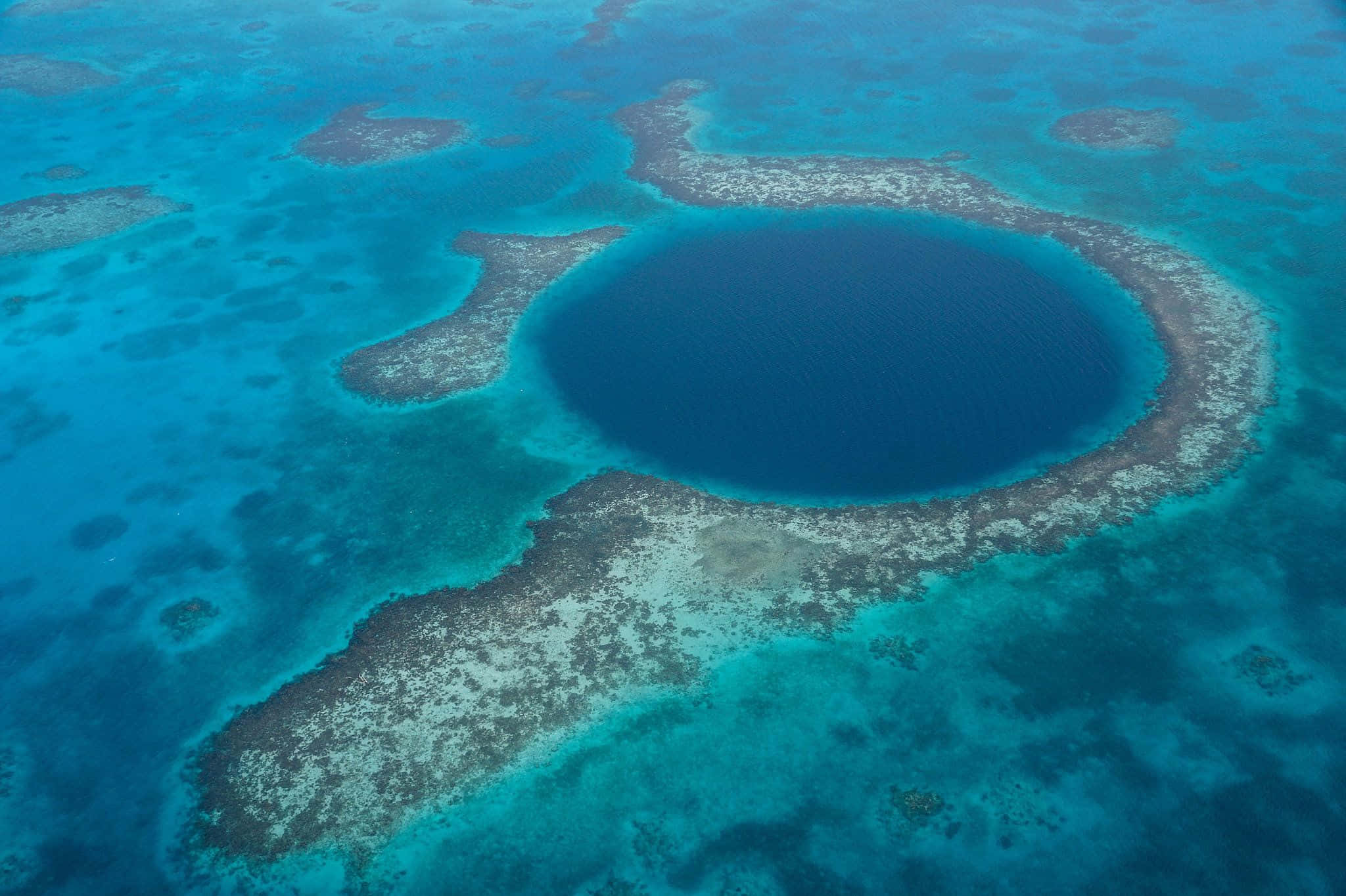 Blue Hole 桌布 壁紙 — 俯瞰一個令人驚嘆的圓形藍色潟湖，周圍環繞著充滿活力的綠松石珊瑚礁。