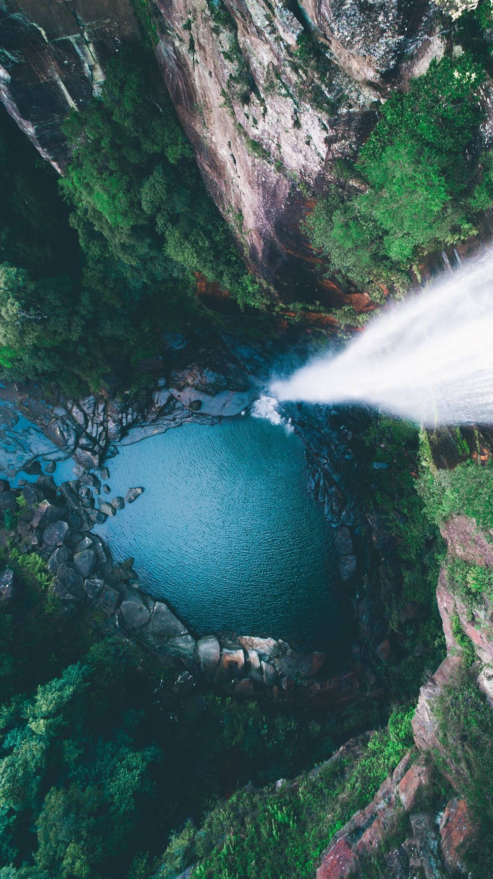 瀑布 桌布 壁紙 — 俯瞰一個強大的瀑布傾瀉入一個翠綠峽谷中的碧綠水池。