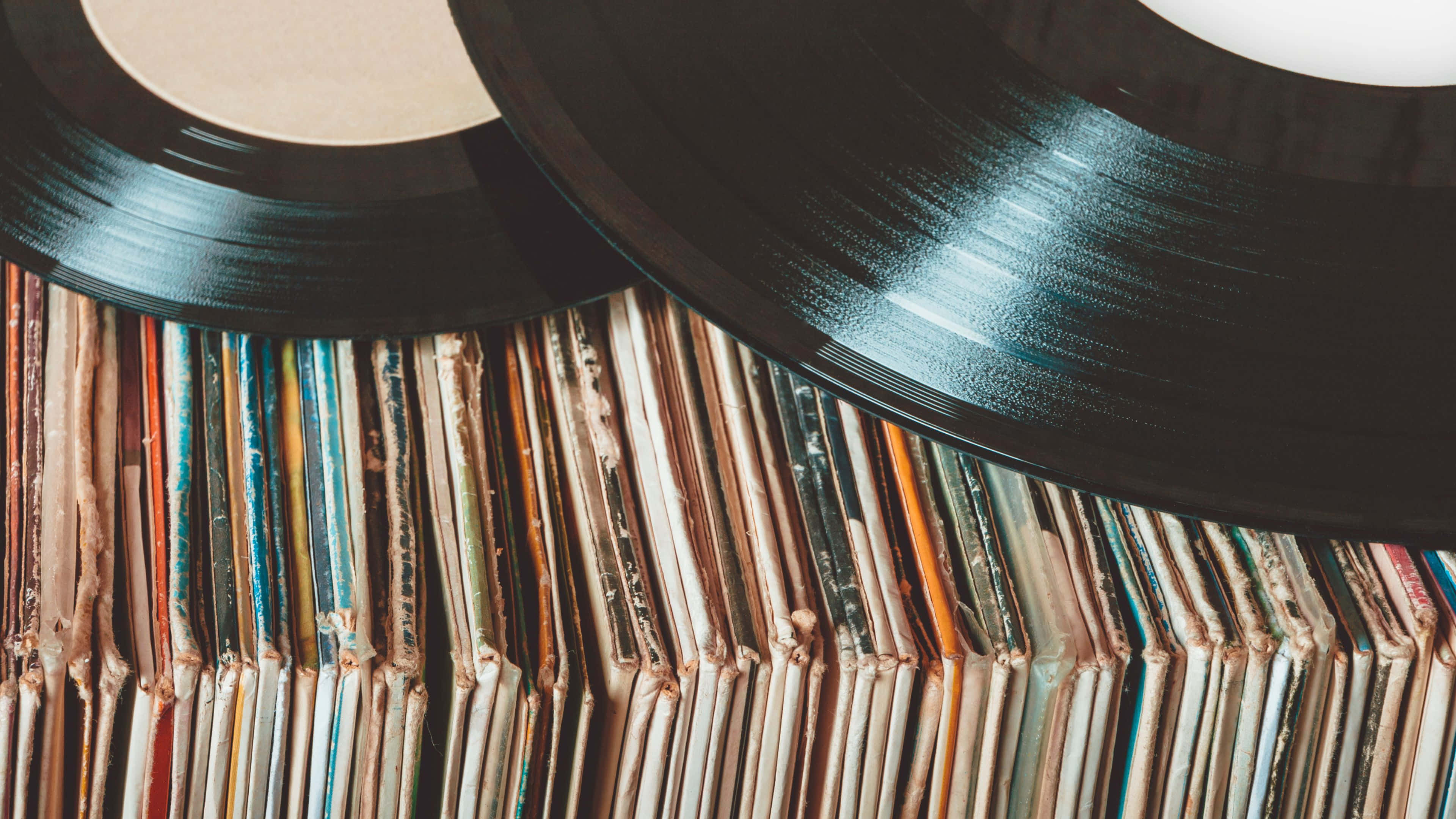 record 桌布 壁紙 — 俯瞰圖：復古黑膠唱片疊在色彩繽紛的唱片封套上。