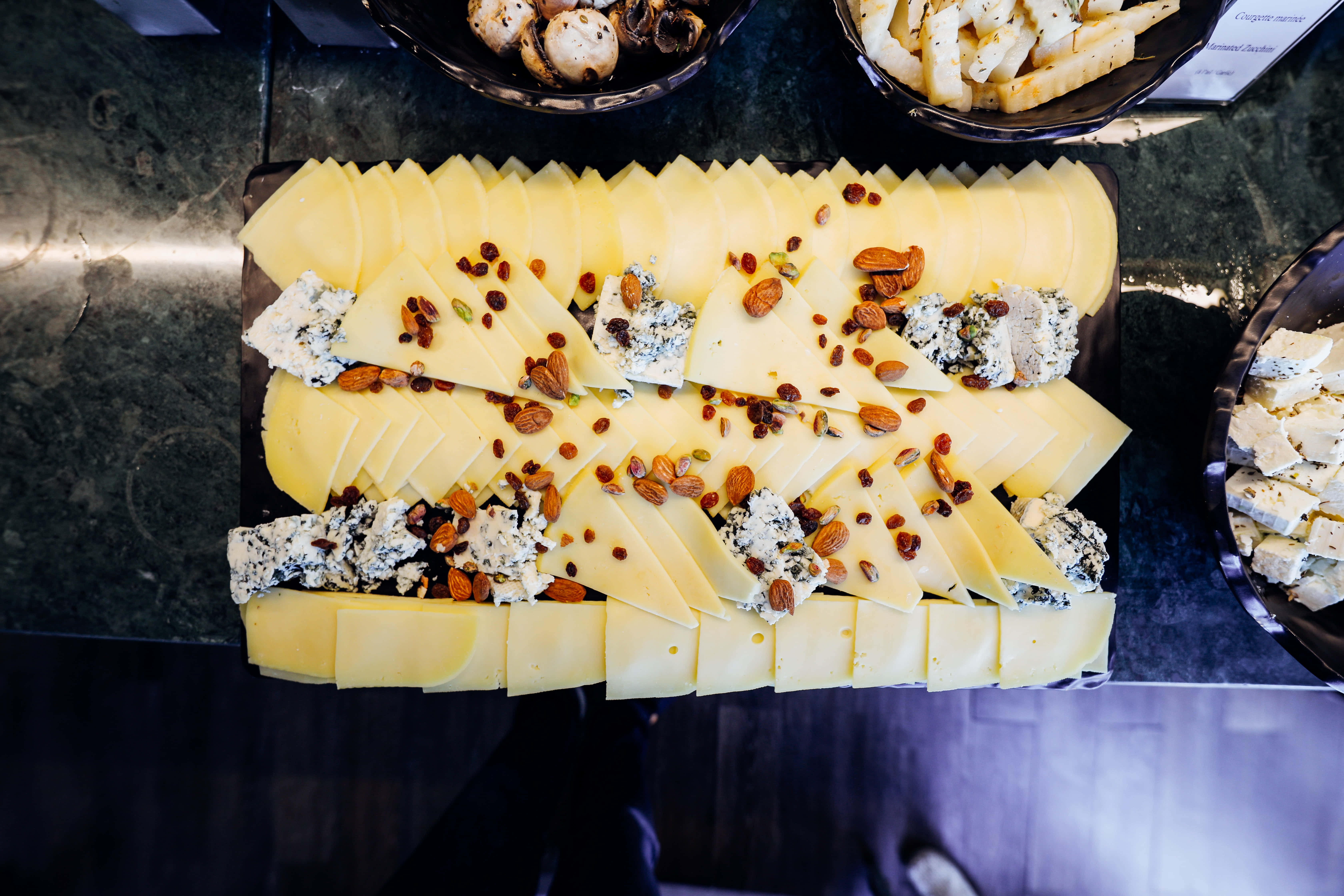 Cheese 桌布 壁紙 — 俯瞰圖：深色大理石枱面上擺放著切片黃芝士、藍芝士塊、杏仁和提子乾的美食芝士板。
