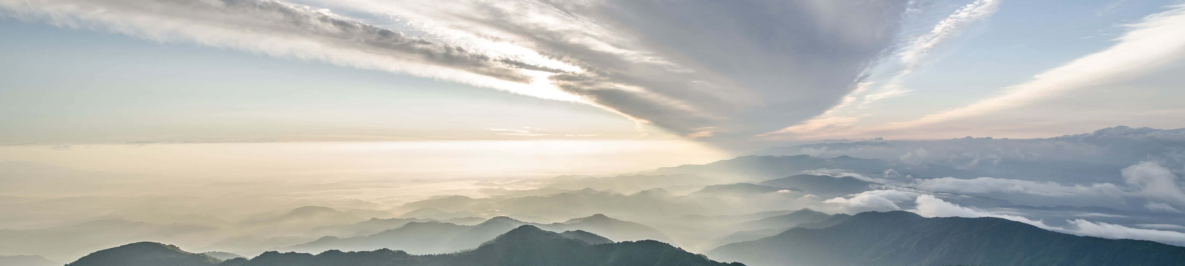 霧氣籠罩的山峰日出，下方有雲層