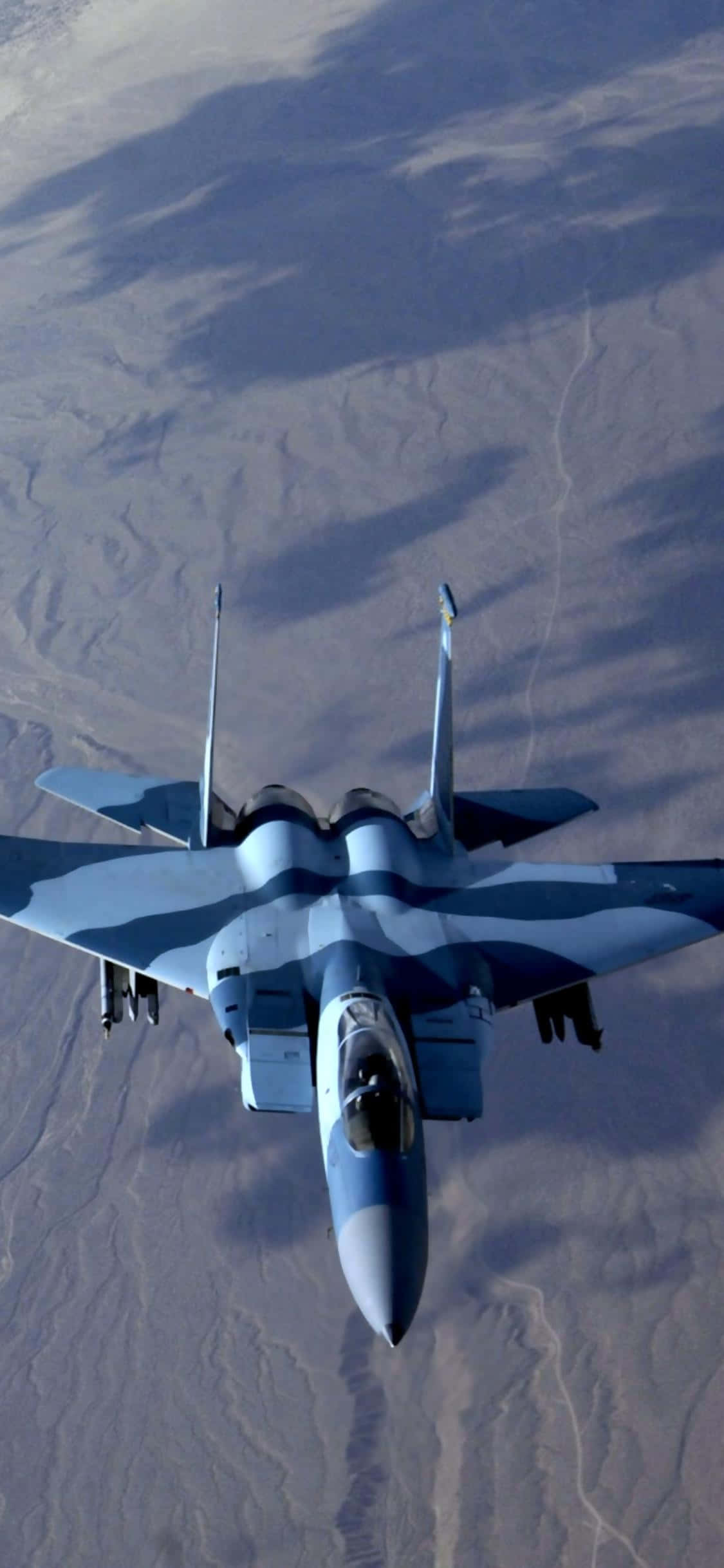 俯瞰角度軍用飛機安卓巨無霸背景 壁紙 — 一架戰鬥機在頭頂翱翔，在下方廣闊的沙漠景觀上投下陰影。