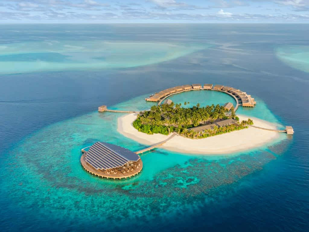 Maldives Island 桌布 壁紙 — 俯瞰豪華水上度假島嶼，擁有碧綠潟湖和珊瑚礁，四周環繞著深藍色海洋。