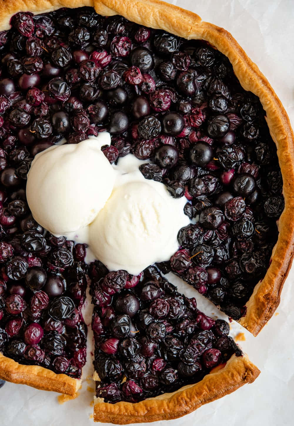 Blueberries Tart 桌布 壁紙 — 俯瞰鏡頭下，一個金黃色的藍莓批，上面有兩球正在融化的雲呢拿雪糕。