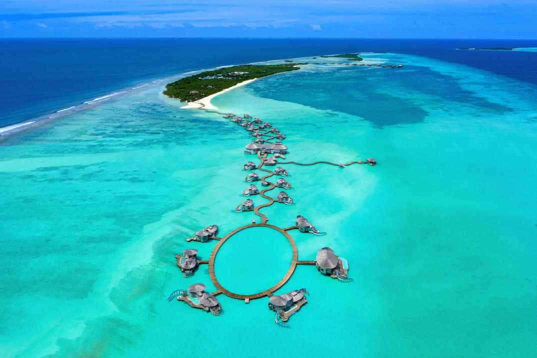 Maldives Island 桌布 壁紙 — 俯瞰鬱鬱蔥蔥的熱帶島嶼周圍碧綠海水中的水上平房。