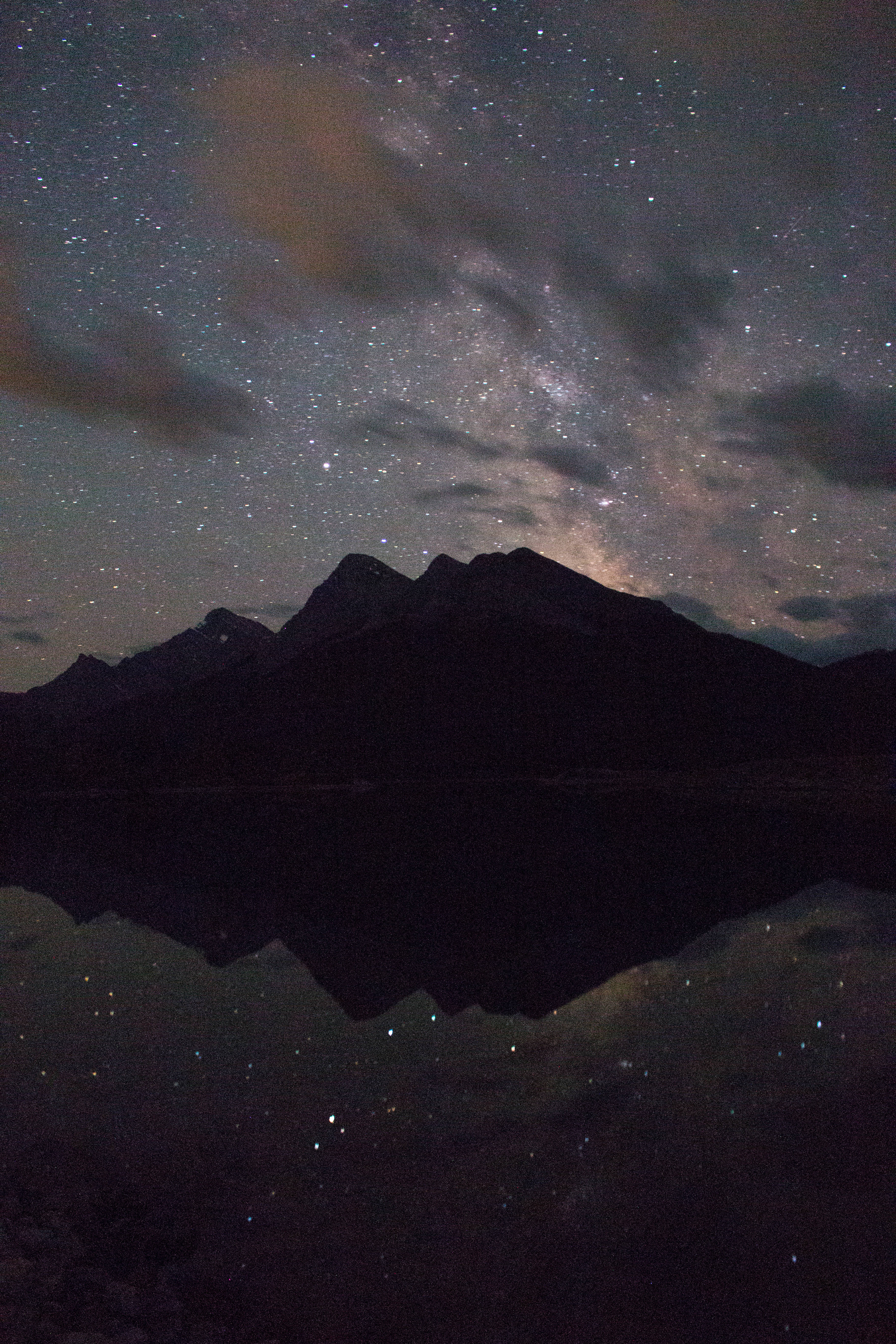 倒影山海手機背景 壁紙 — 繁星點點的夜空，銀河拱跨山脈，完美倒映在下方平靜的湖面上。