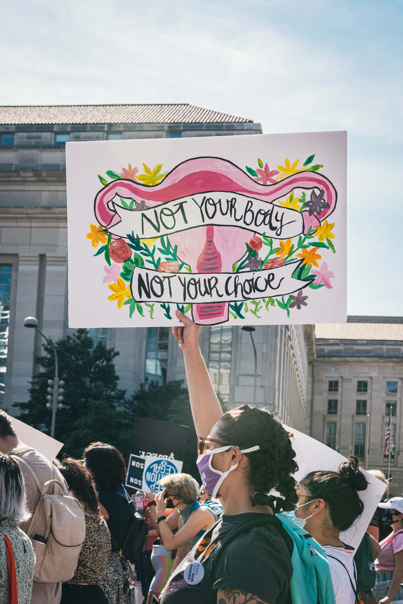 抗議者手持花卉抗議標語牌，上面寫著 Not Your Body Not Your Choice