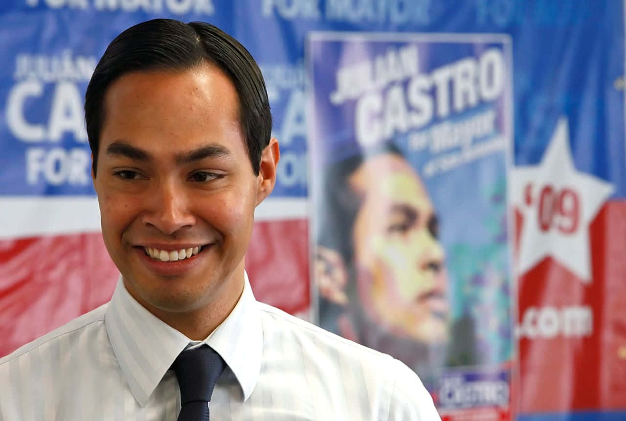朱利安·卡斯特羅在競選活動中微笑，身後有政治海報。