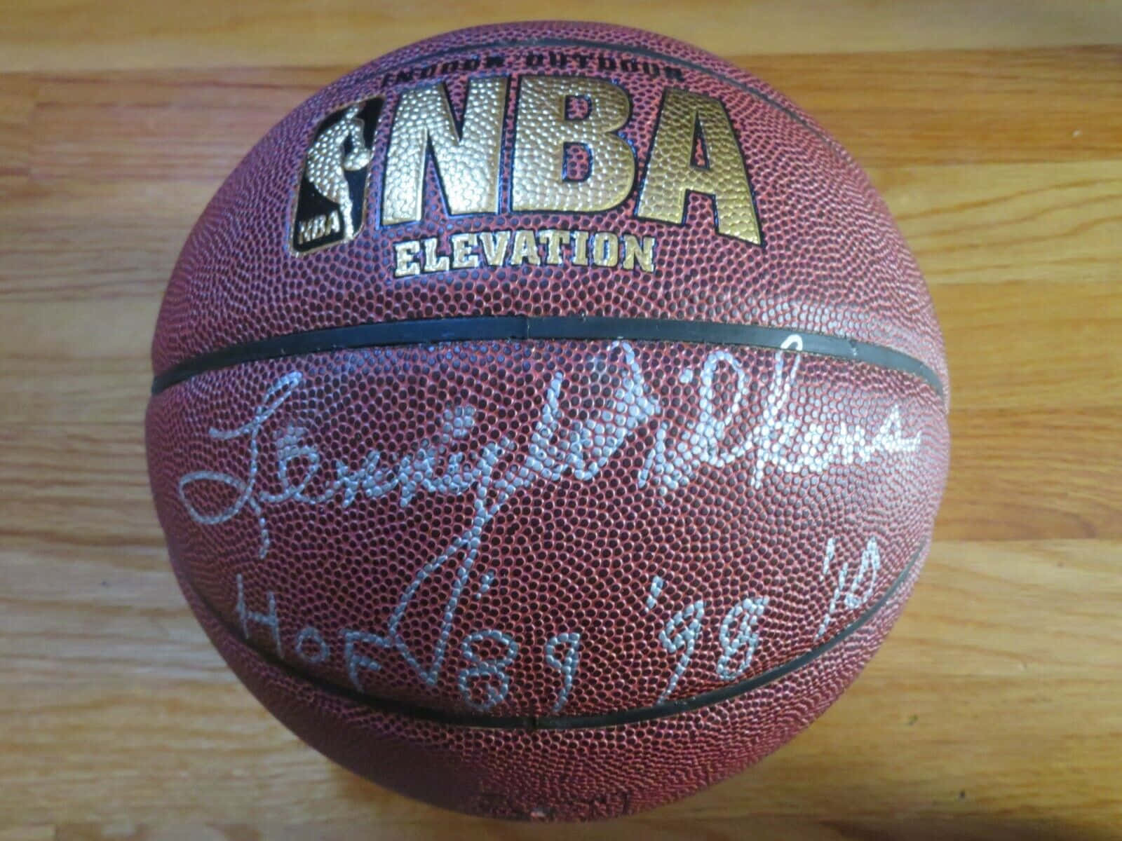 簽名NBA籃球，上面有Lenny Wilkens簽名，放喺木地板上面。
