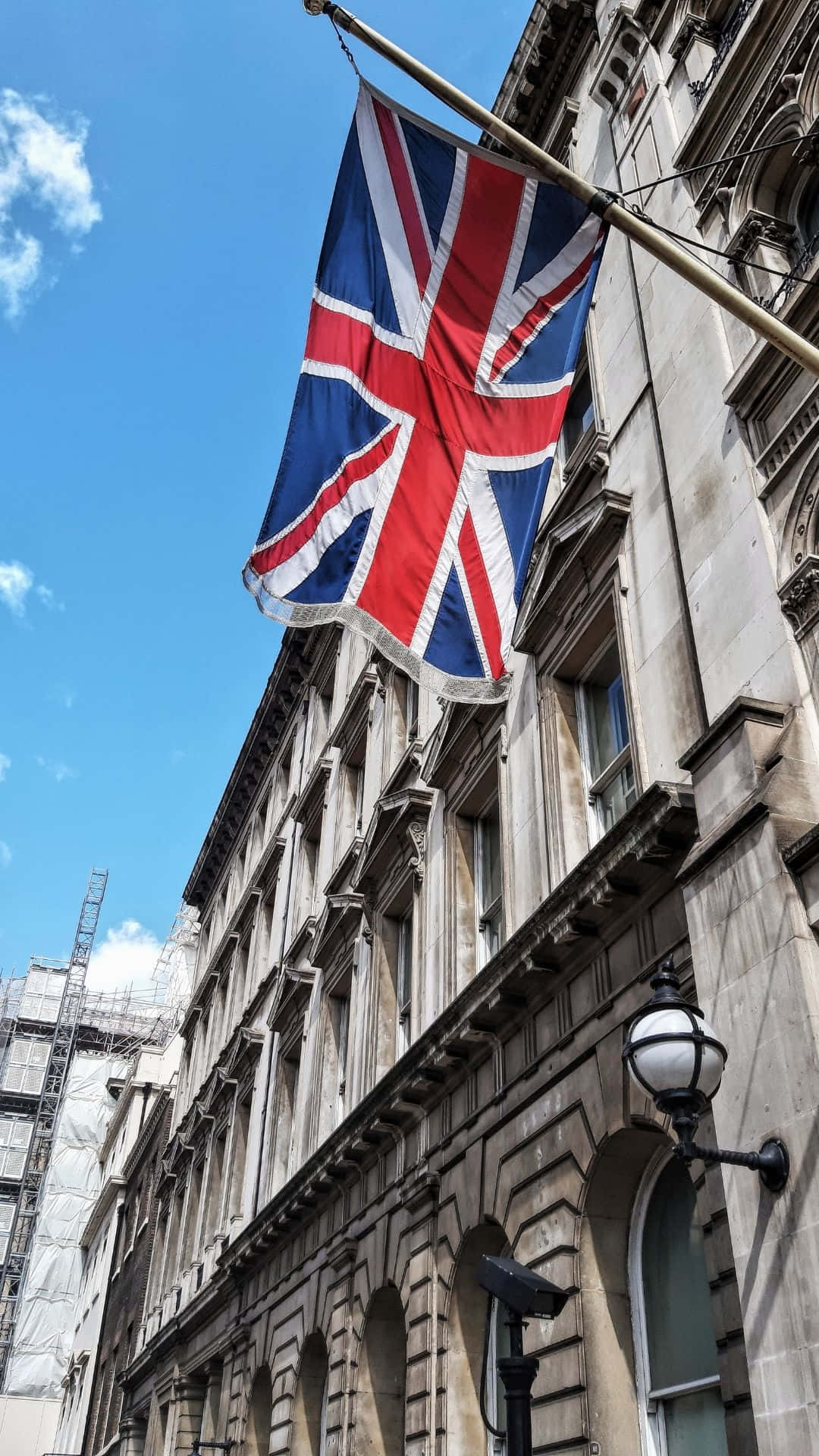 英國國旗在晴朗的藍天下飄揚在一座歷史石建築上。