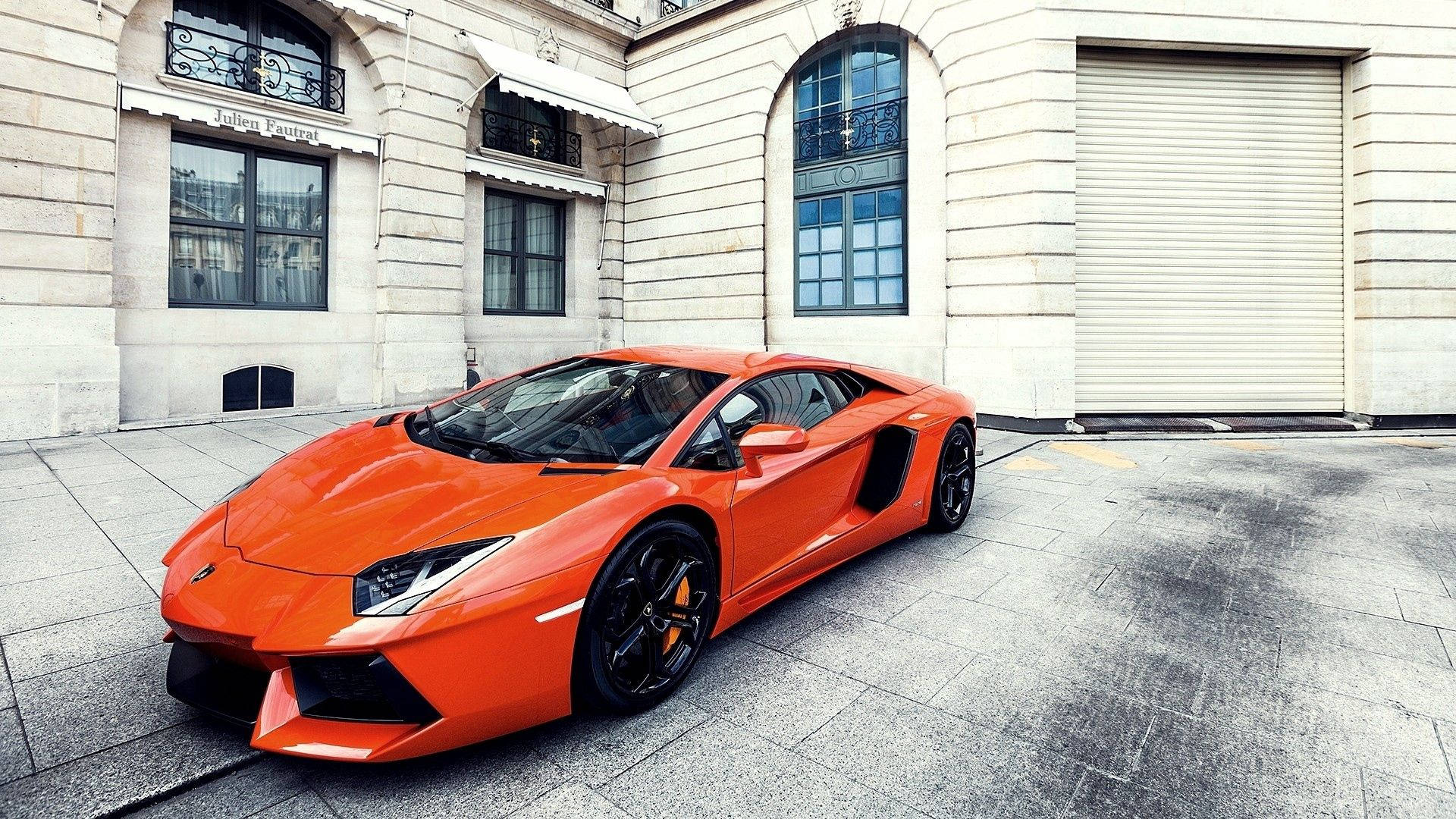 橙色林寶堅尼Aventador停泊在歐洲建築前的石鋪路面上。