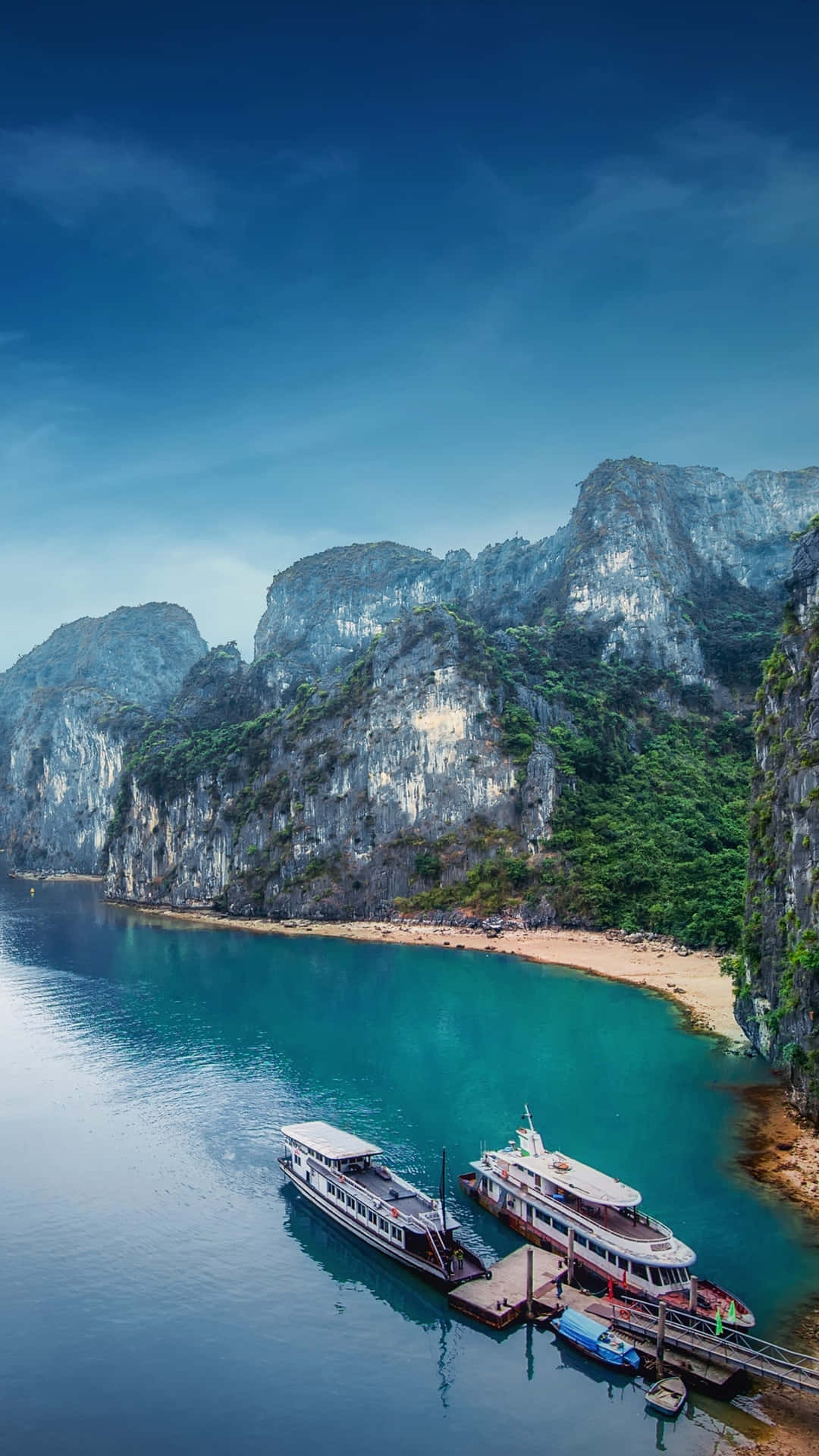 船隻停泊在碧綠海灣，四周環繞高聳的石灰岩懸崖。