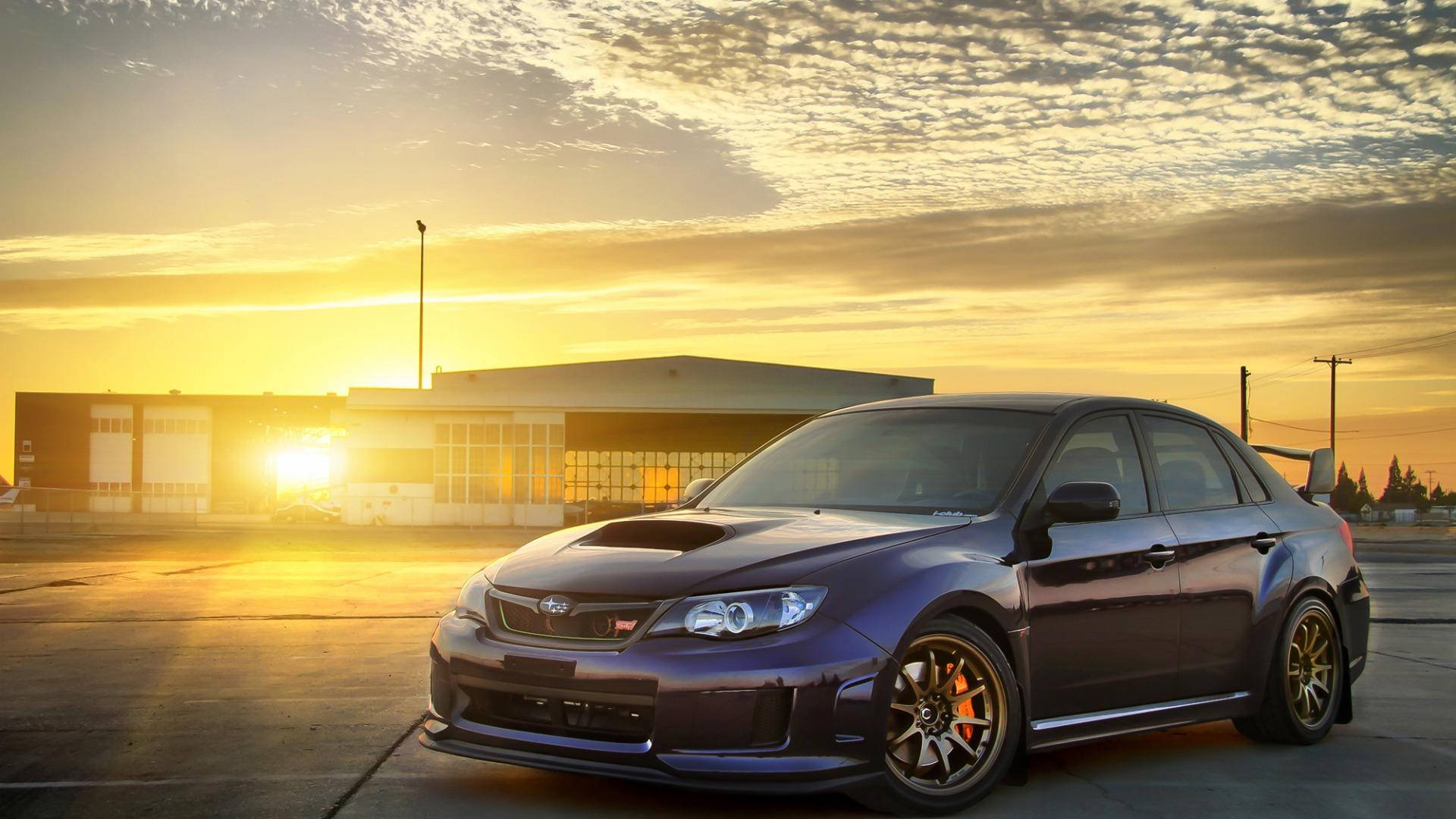 停泊於停機坪的斯巴魯Impreza 壁紙 — 一架深紫色Subaru WRX STI停泊在混凝土上，金色夕陽光芒在現代建築後方閃耀。