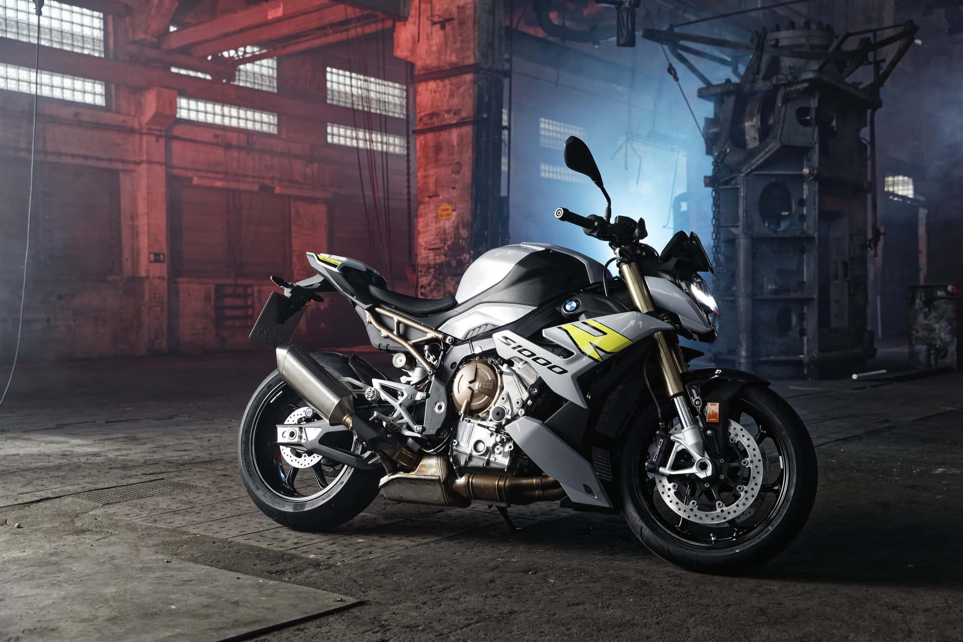 煙霧瀰漫的工業倉庫中的銀色和黃色BMW S1000R電單車。