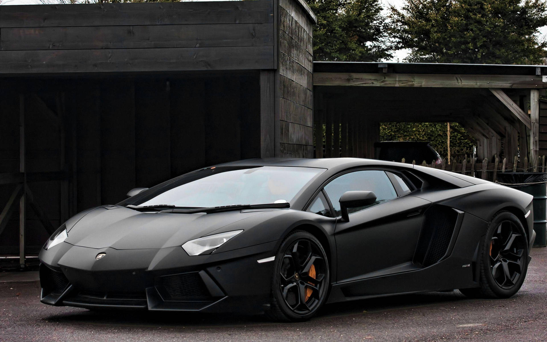 啞光黑色林寶堅尼 Aventador 停泊在木建築附近