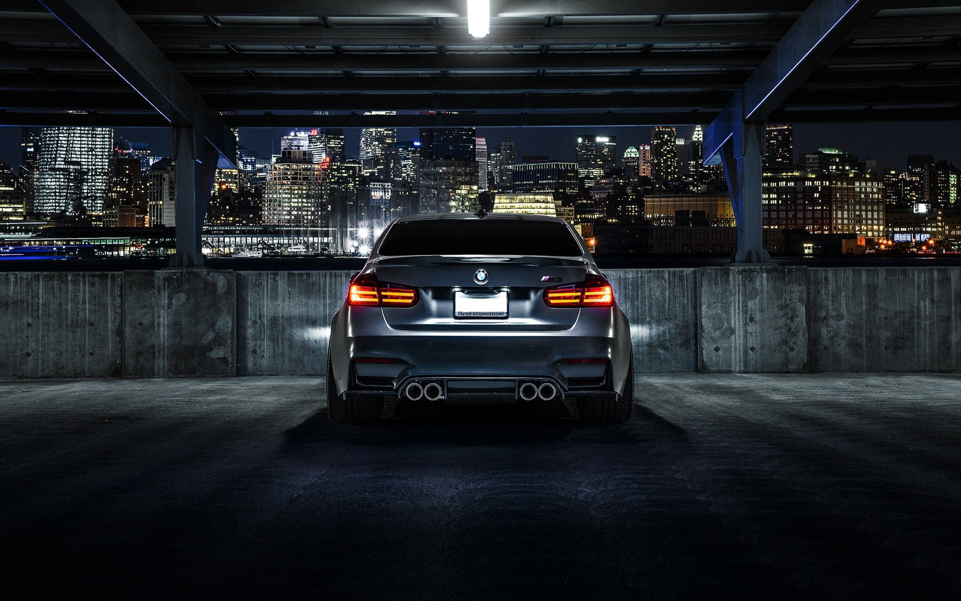 時尚的銀色BMW M5在夜間停泊，俯瞰著充滿活力的城市天際線。
