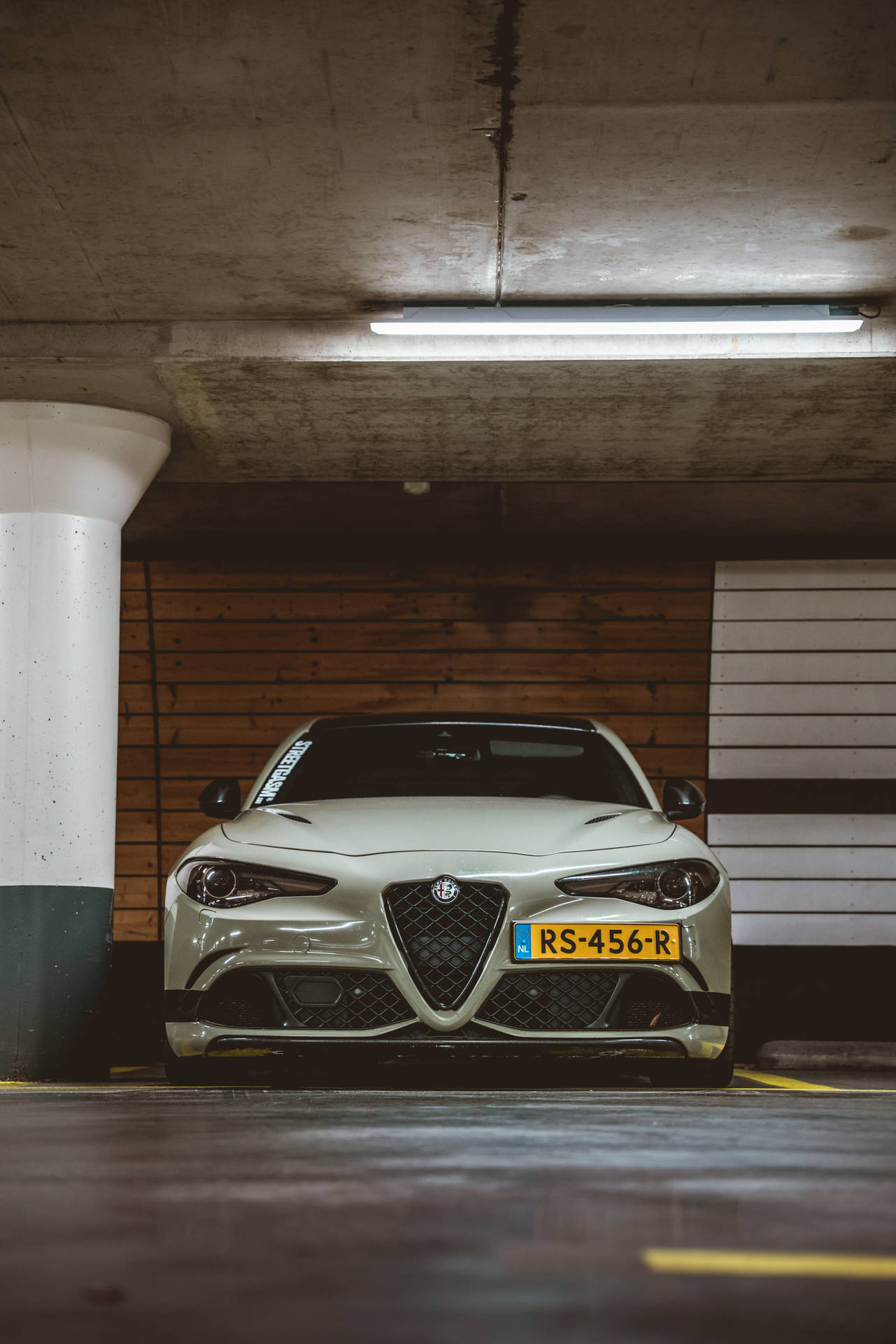 銀色Alfa Romeo跑車停在有木牆的地下車庫中。